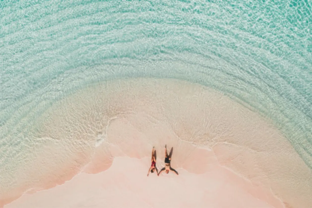 couples who travel together lying on pink beach in komodo national park